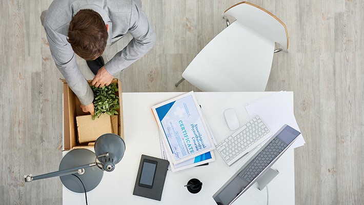 Homem mexendo em sua mesa de trabalho visto de cima.